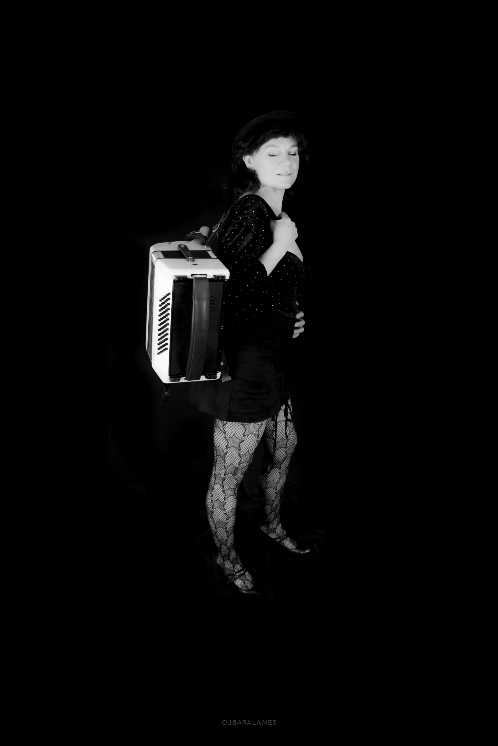 ✔️ “Zwart-wit portret staand van Cato Fluitsma met accordeon tegen zwarte achtergrond”